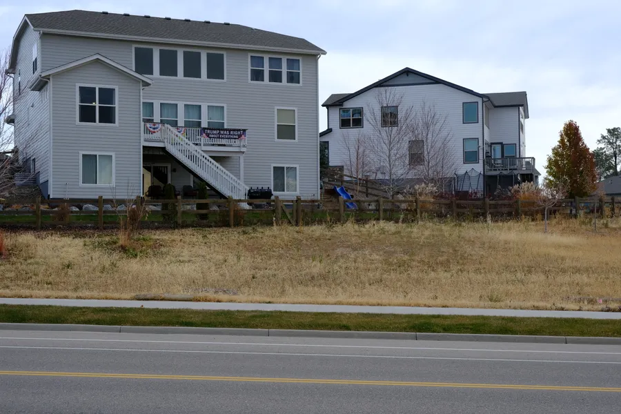 back of house by large empty area and road