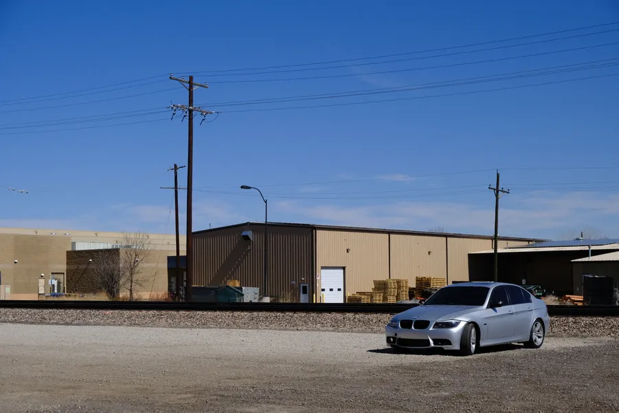 car in empty lot by train tracks